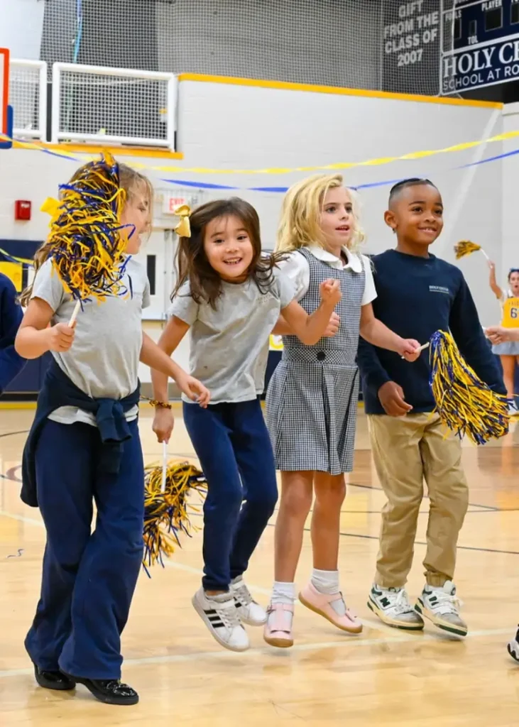 Young Holy Child students cheering with pom-poms in the gymnasium